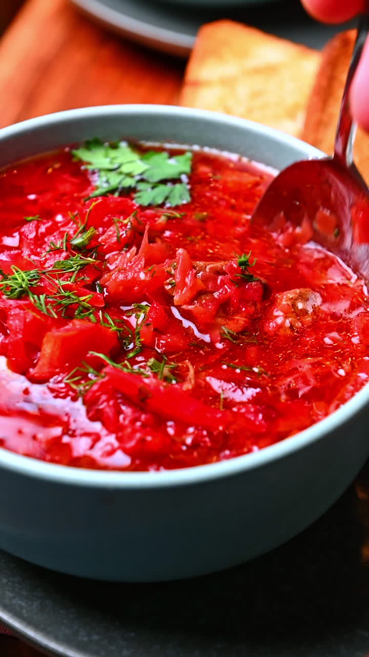 Hot beet soup with herbs. Hot beet soup topped with herbs served in a ceramic bowl