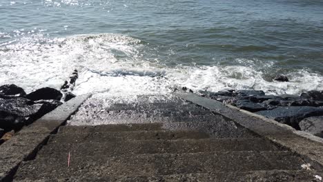 old stone stair way to blue swollen sea bali indonesia mysterious ocean waves 60 fps