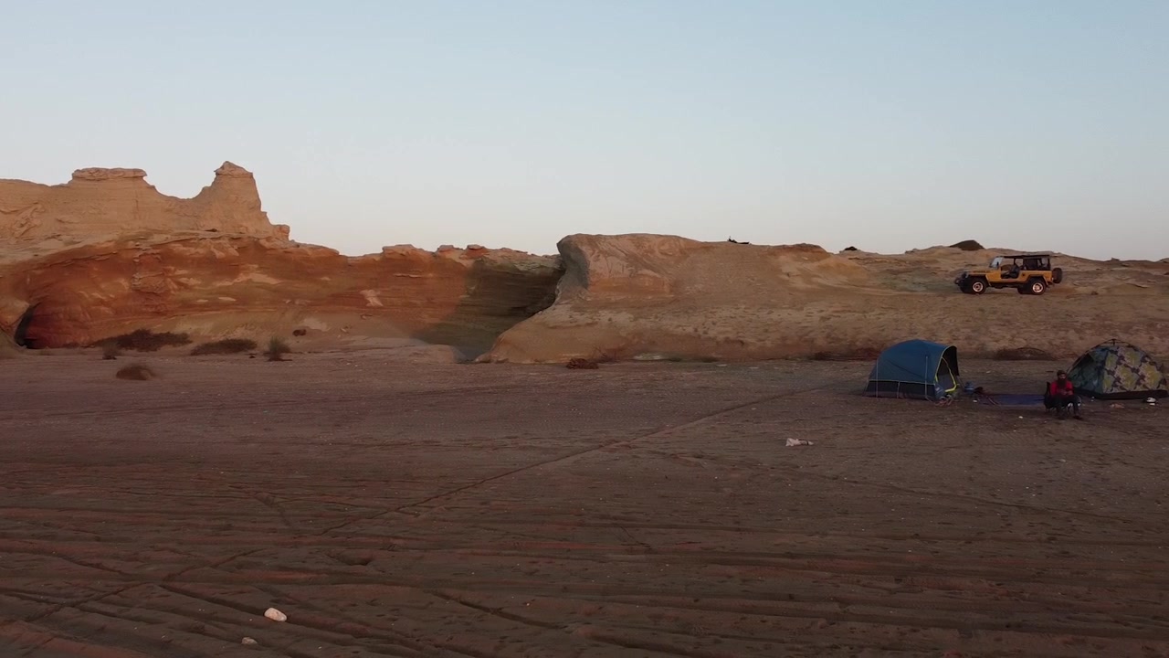 Panning shot of beautiful Sapat Beach in Balochistan with camp tents set along the beachside during evening time.