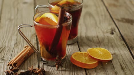 video of cups of hot tea with cinnamon and lemon over wooden background