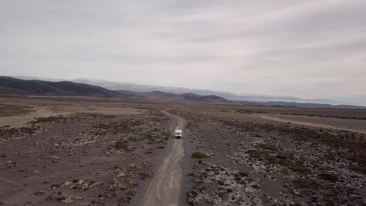 An old camper van drives through the desert at Tukino Access Road, Tongariro National Park - Rangipo Desert. Its a cloudy day.