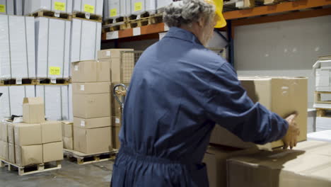 focused man and diverse female employees working together and rearranging cardboard boxes in warehouse