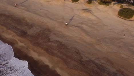 Alta-Vista-Aérea-En-órbita-De-Los-Puestos-De-Vida-En-La-Playa-En-Una-Hermosa-Mañana-De-Amanecer-En-Mar-De-Las-Pampas,-Sudamérica