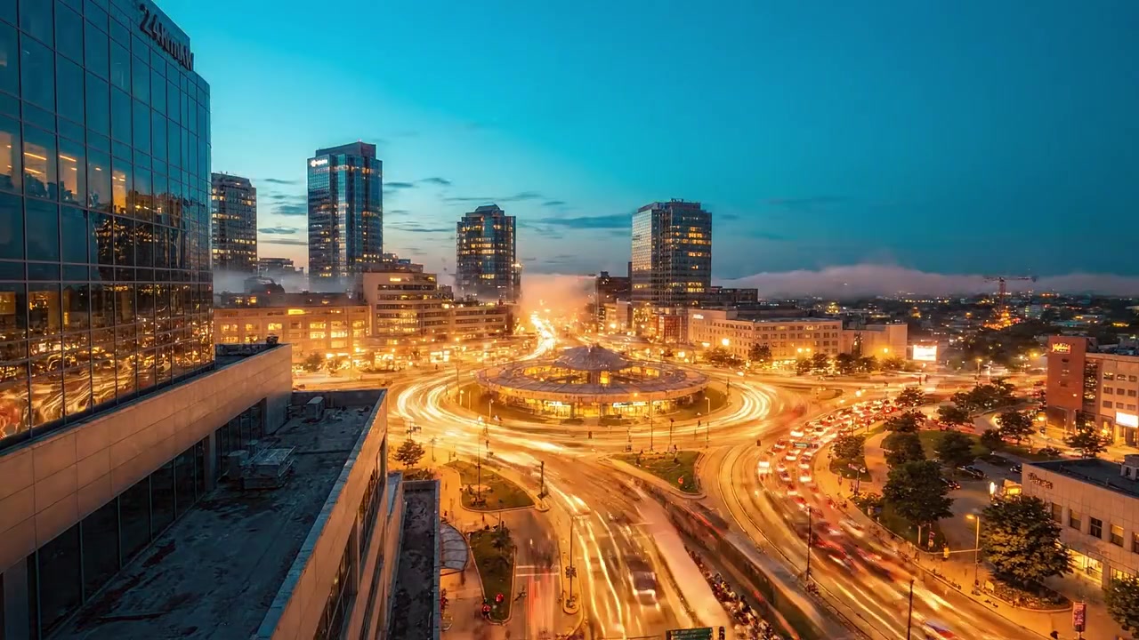 Una splendida transizione dal giorno alla notte: paesaggio urbano che cattura il traffico, una rotonda, le luci della città e cieli espressivi durante l'ora d'oro.