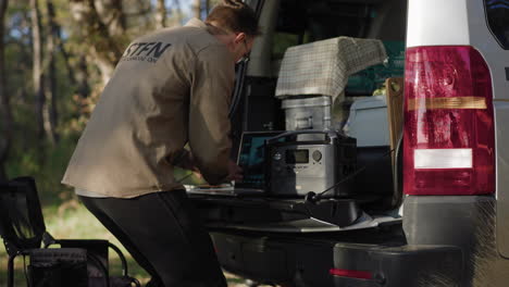 digital-nomad-sitting-down-at-trunk-lid-to-work-on-his-computer