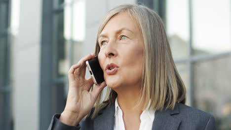 close up view of mature businesswoman talking on the phone in the street 1