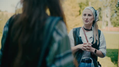 woman wearing bandana and talking to friend