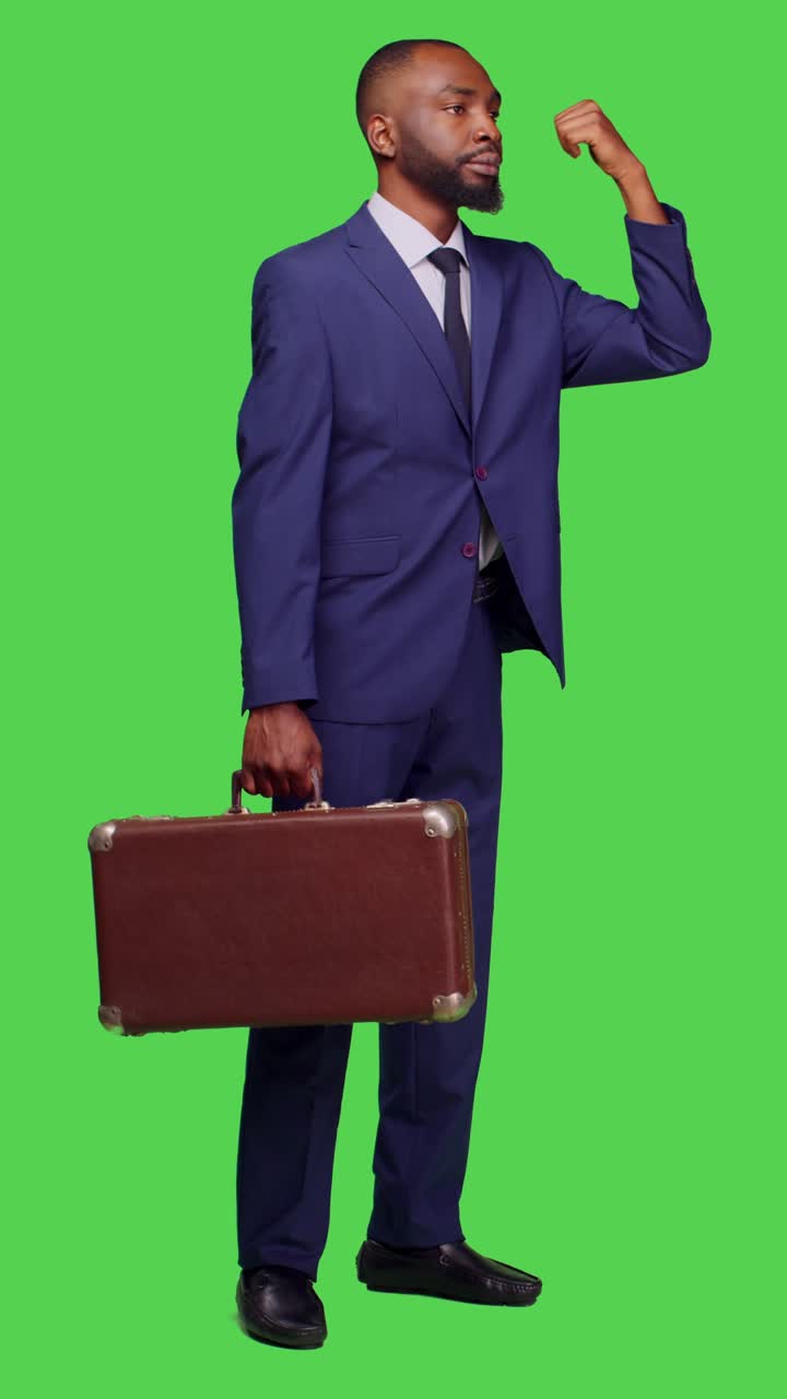 Vertical video: Side view of company employee with suitcase hitchhicking on camera