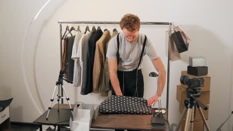 joven agradable empaca ropa para enviar un paquete