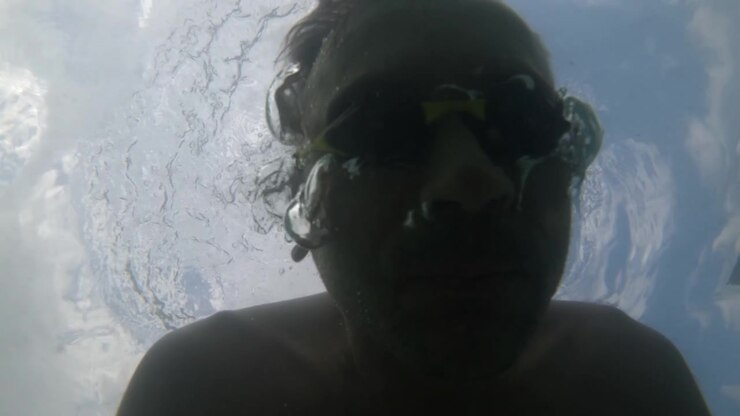 Undervandsbillede i slowmotion af en svømmers silhuet, der bryder havoverfladen, Côte d'Azur, Frankrig