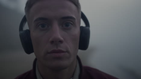 handsome guy listening music in headphones. closeup focused man posing at camera