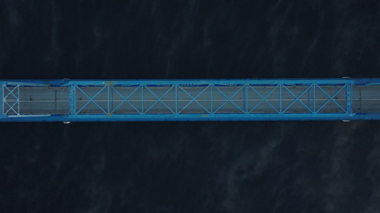 Aerial establishing view of the steel bridge over Lielupe river on a sunny summer morning, fog rising over the river, cars driving, wide birdseye drone shot moving left