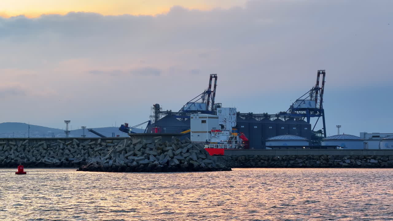 Burgas, Bulgarien, 29 oktober 2025: Lastfartyg dockat i hamn med industriella strukturer i bakgrunden. Ett lastfartyg ligger för ankar i en hamn med stora byggnader och utrustning