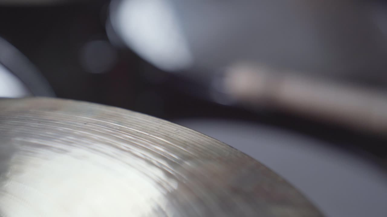 Drumsticks rapidly hitting hi-hat cymbal. Close up handheld.