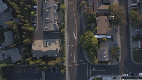 overhead drone view of a quiet neighborhood street with homes, cars parked along the curb, and trees lining the road. ideal for real estate, urban planning, or suburban lifestyle visuals