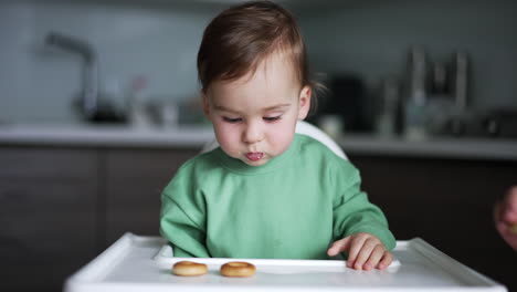 baby eating cookies in high chair