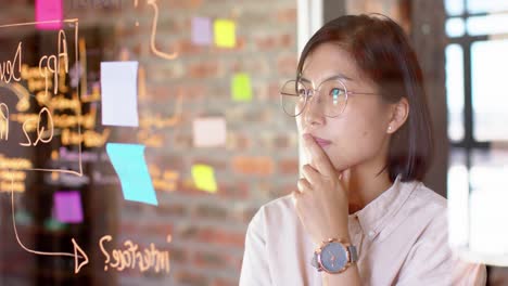 thoughtful asian creative businesswoman brainstorming ideas in casual office, slow motion