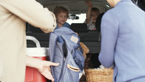 Family-Goes-On-Vacation,-Parents-Put-Luggage-In-The-Trunk-And-Little-Children-Wait-Sitting-Inside-The-Car-1