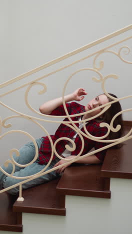 exhausted woman strokes head lying on steps. frustrated lady does self calming motions to deal with stress on stairs. mental health care importance
