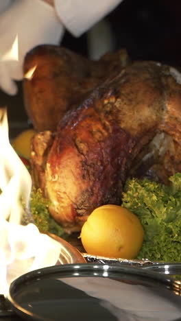 chef is cutting the baked chicken with a knife and putting the slices on the plates near the fire in the street on the summer terrace of the cafe vertical video