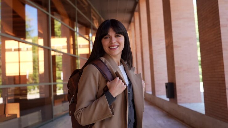 Giovane donna felice con lo zaino che sorride alla fotocamera nel campus.