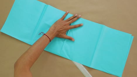 hand cutting blue tissue paper sheets with precision using a rulers edge for crafting