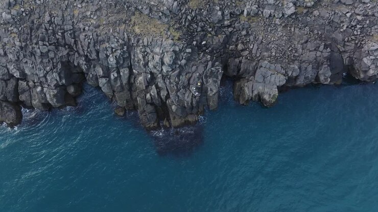 Vista aerea dall'alto di calme acque islandesi, rocce basaltiche sulla costa - Marea atlantica