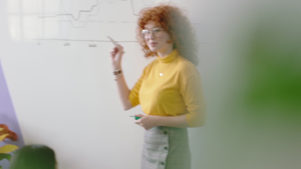 giovane donna d'affari dai capelli rossi che insegna un gruppo di studenti che mostrano le statistiche del mercato sulla lavagna condividendo dati grafici squadra diversificata brainstorming idee creative in ufficio lezione