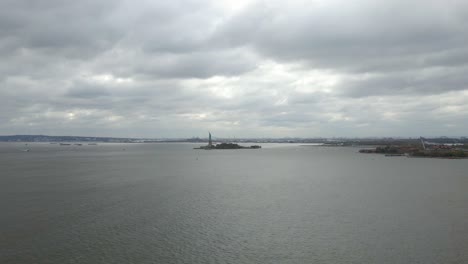 Aerial-view-away-from-the-statue-of-Liberty,-in-cloudy-New-York,-USA---pull-back,-drone-shot