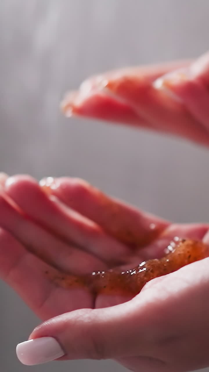 mujer sostiene un puñado de exfoliante en la unidad de ducha de primer plano. dama demuestra un producto cosmético exfoliante casero para el cuidado de la piel en el baño. relajación en el spa