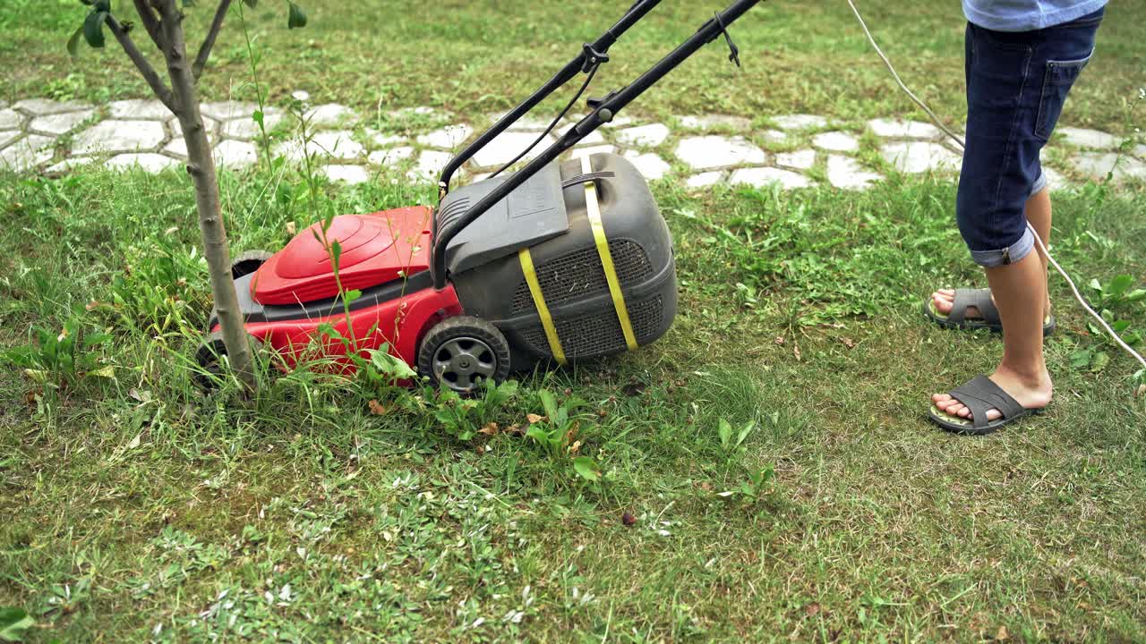 Lawn Mover in action. Lawn mower cut grass. Summer seasonal workers in backyard.