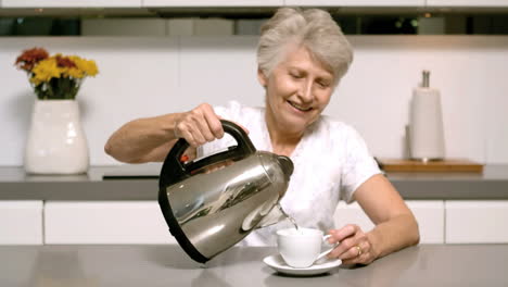 retired woman pouring boiling water from kettle into cup