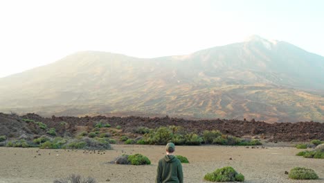 Tilt-up-from-boy-walking-in-desert-to-Teide-volcano,-Tenerife
