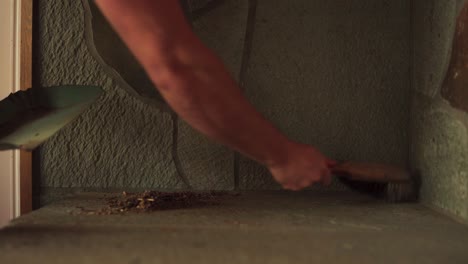 Person's-Arm-Brushing-And-Cleaning-Dirt-From-Concrete-Fireplace