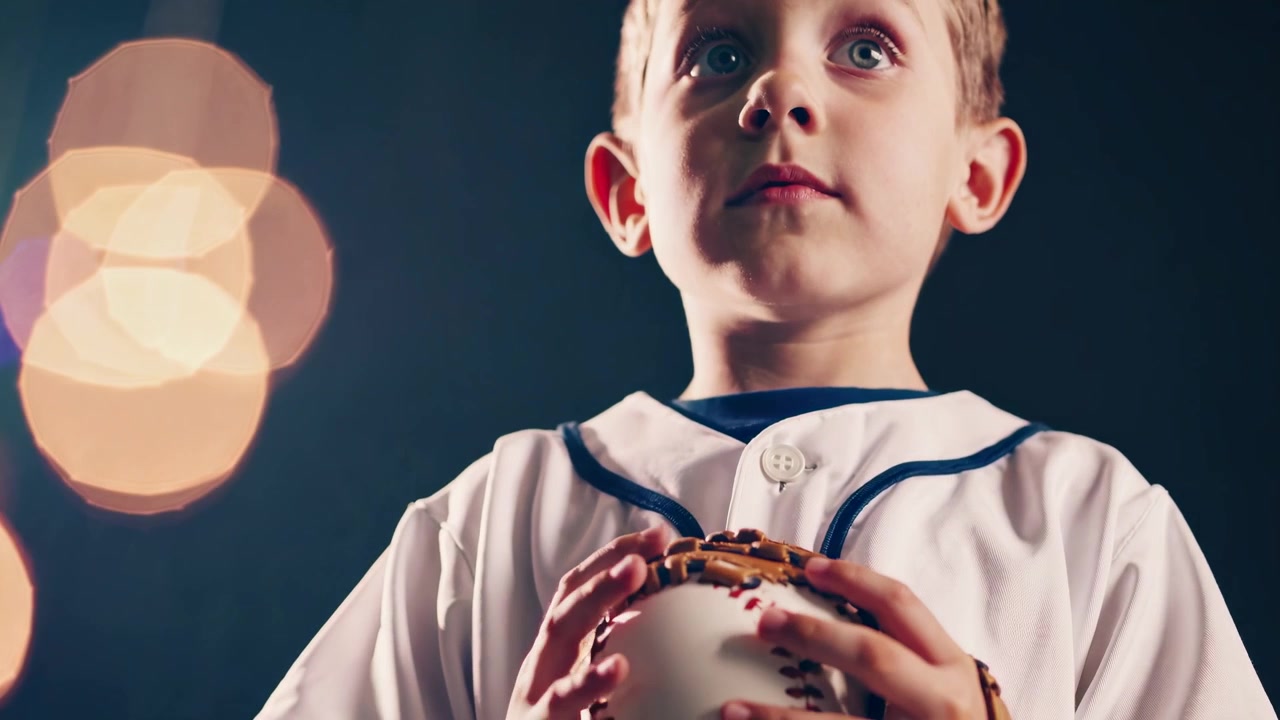 Giovane ragazzo in uniforme da baseball che tiene una palla