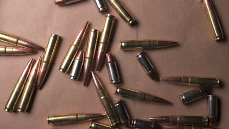 slow motion footage of rifle shells and pistol bullets falling onto table