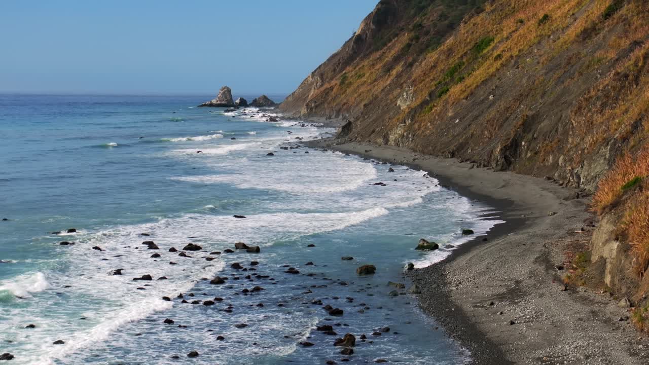 Waves crashing surf black sand rugged coastline sunny morning blue sky mist fog layer USAL Beach Campground Lost Coast Trail California Pacific Ocean PNW boulders rocks mountainside backwards motio