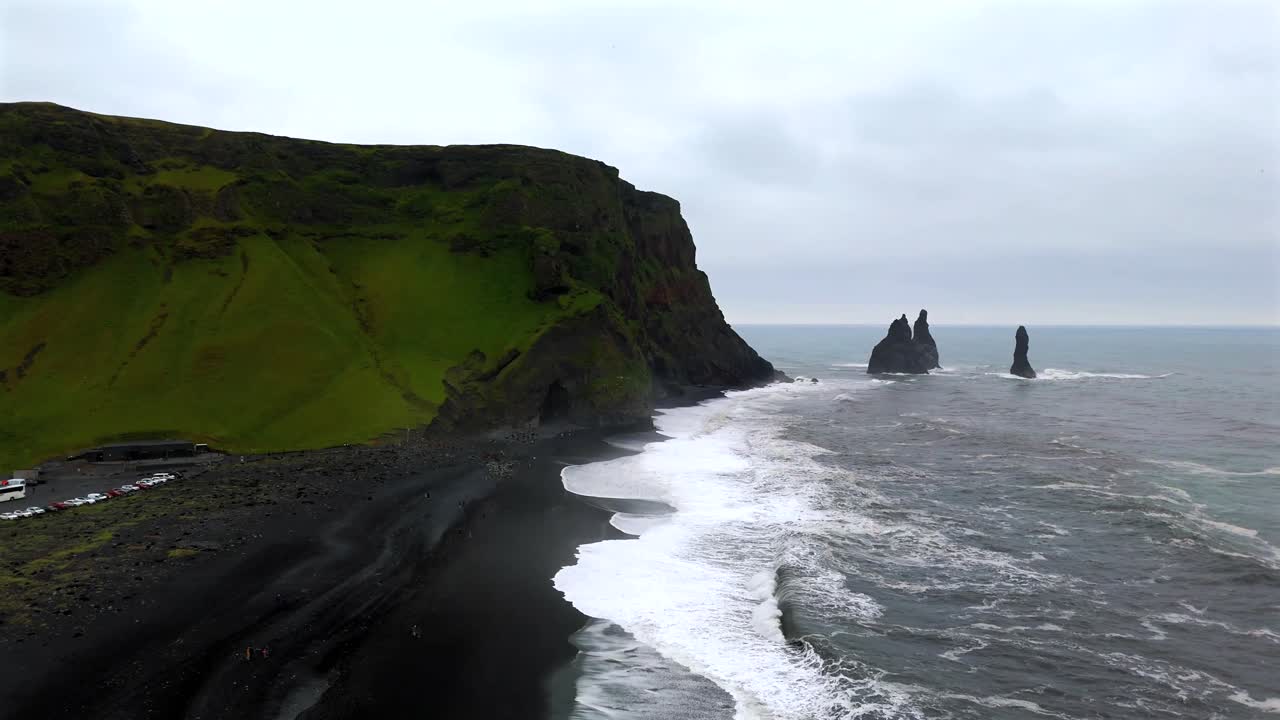 The drone footage showcases Reynisfjara’s iconic basalt sea stacks, standing tall against the wild ocean, offering a stunning glimpse of Iceland’s natural wonders.