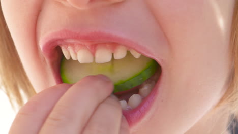Close-up,-mouth-of-a-child-biting-and-chewing-a-fresh-slice-of-cucumber