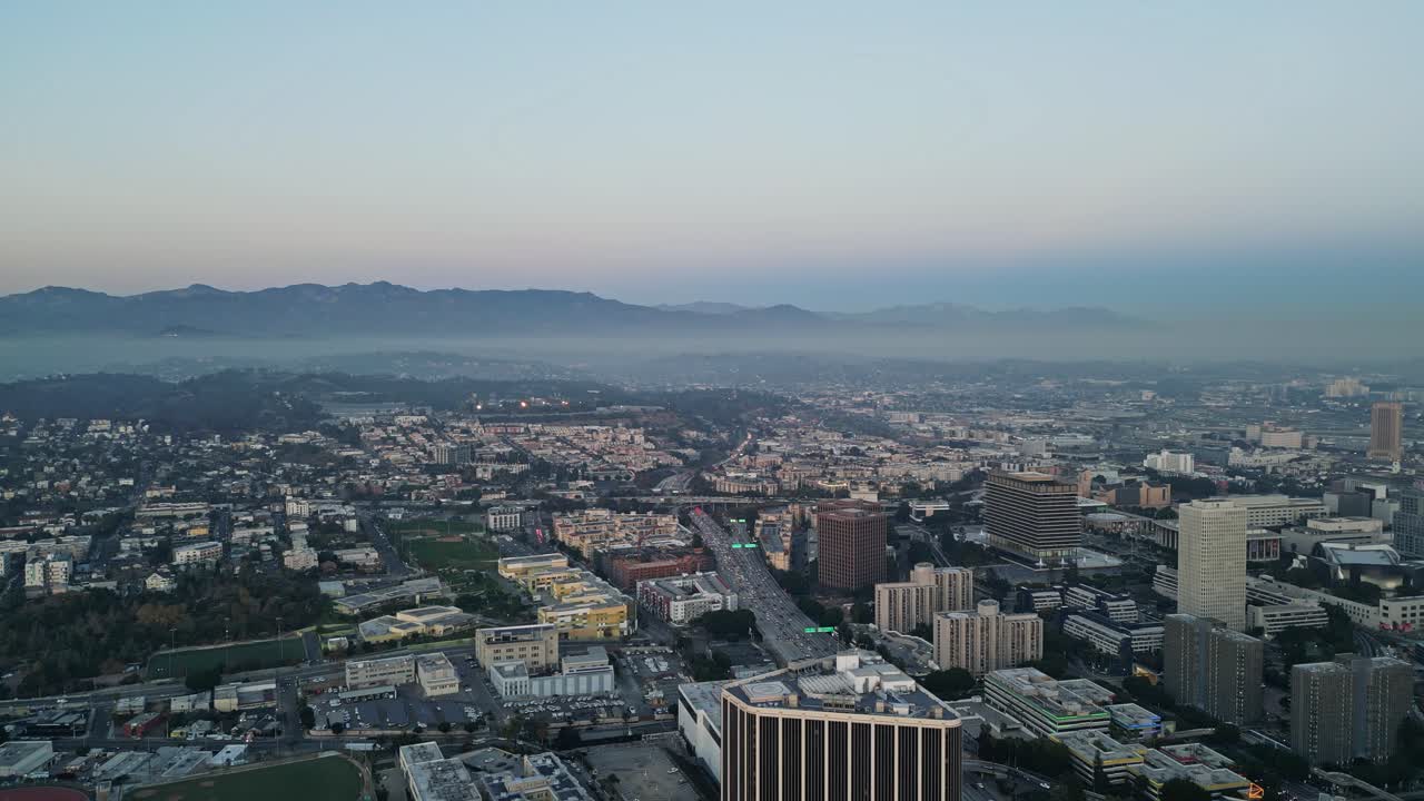 A drone shot of downtown Los Angeles at sunset, with the mountains creating a stunning backdrop.