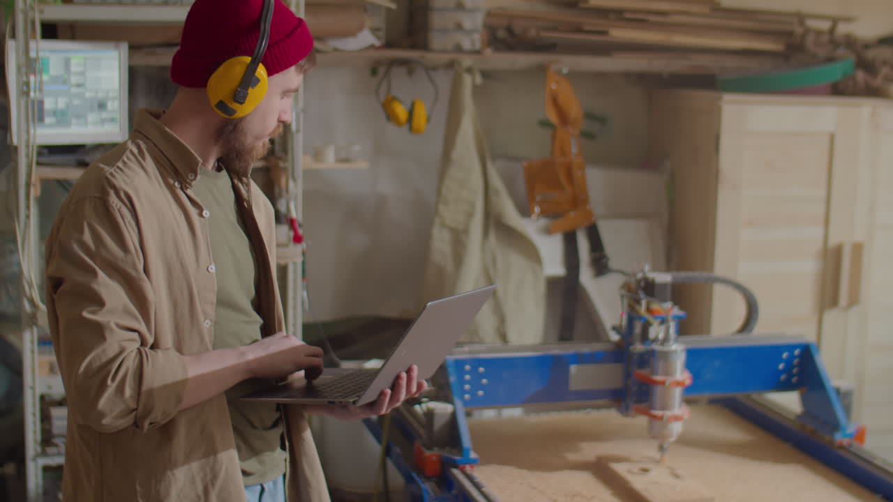 Carpenter Working with Laptop in Woodworking Workshop