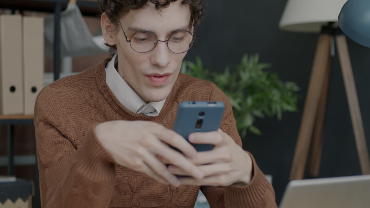 Young Man Texting on Smartphone in Office