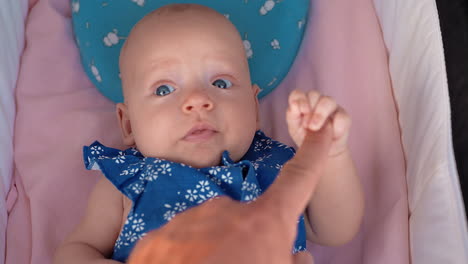 baby lying in pram and holding fathers finger