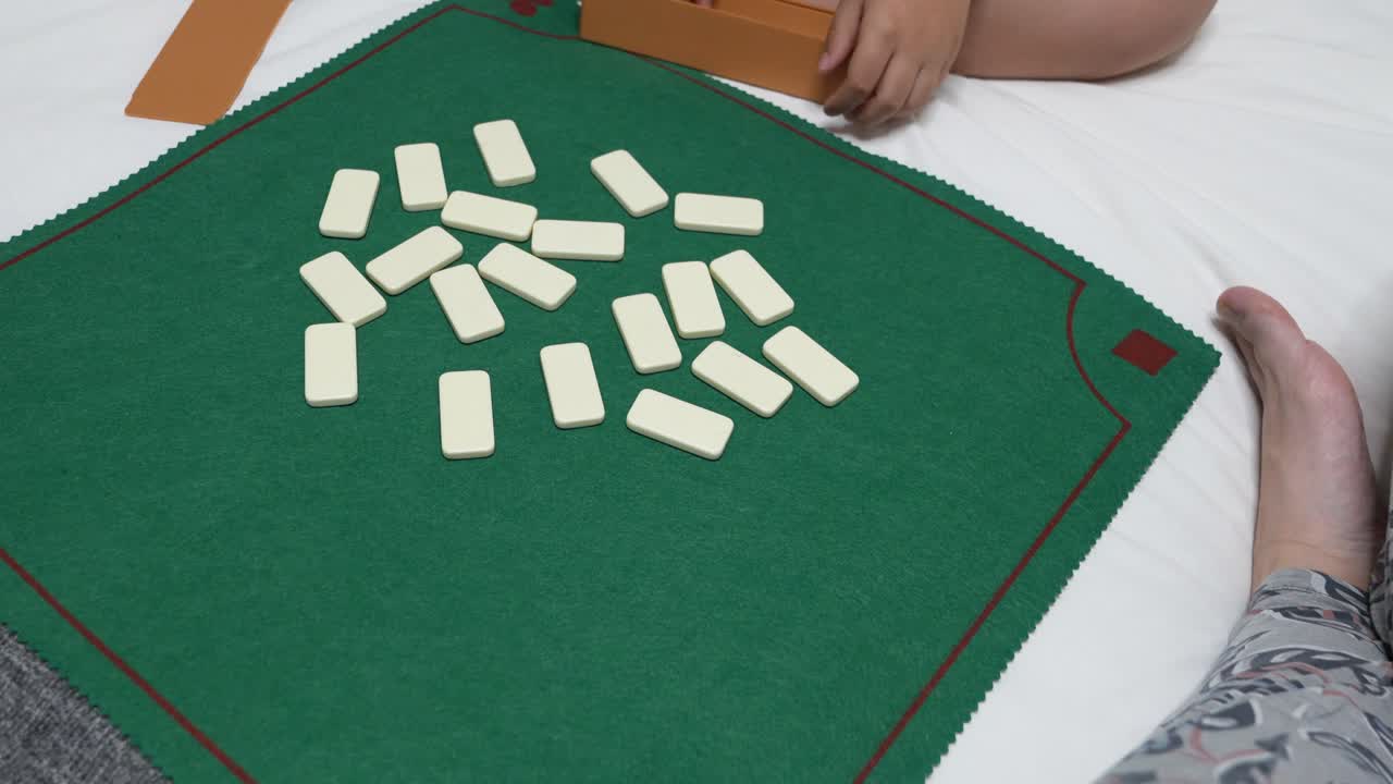 Familie spiller domino på sengen