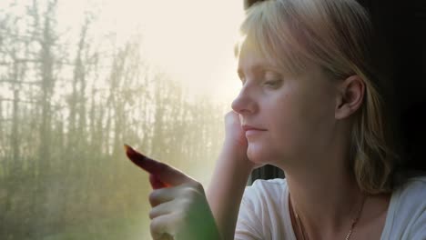 retrato de una mujer joven que viaja en un tren mirando por la ventana los rayos del sol la iluminan