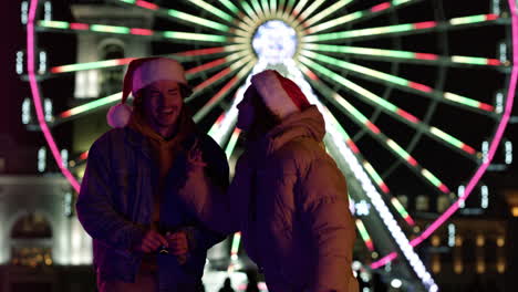 smiling couple laughing on urban street. pair in santa hats having fun outdoor.