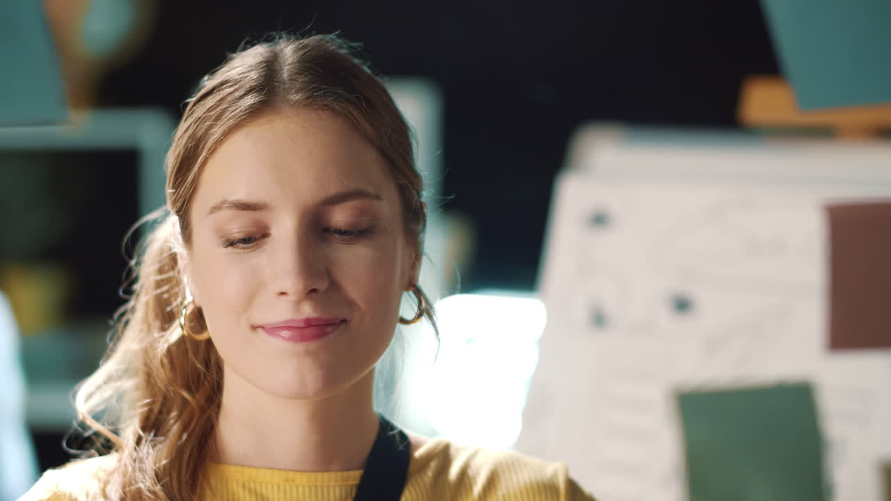 Closeup satisfied businesswoman putting sticker on glass wall in hipster office