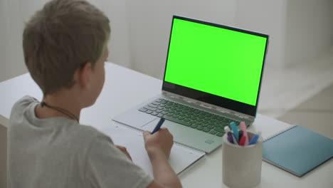 portrait-of-little-schooler-boy-at-home-chatting-online-by-notebook-with-internet-connection-sitting-at-living-room-at-home