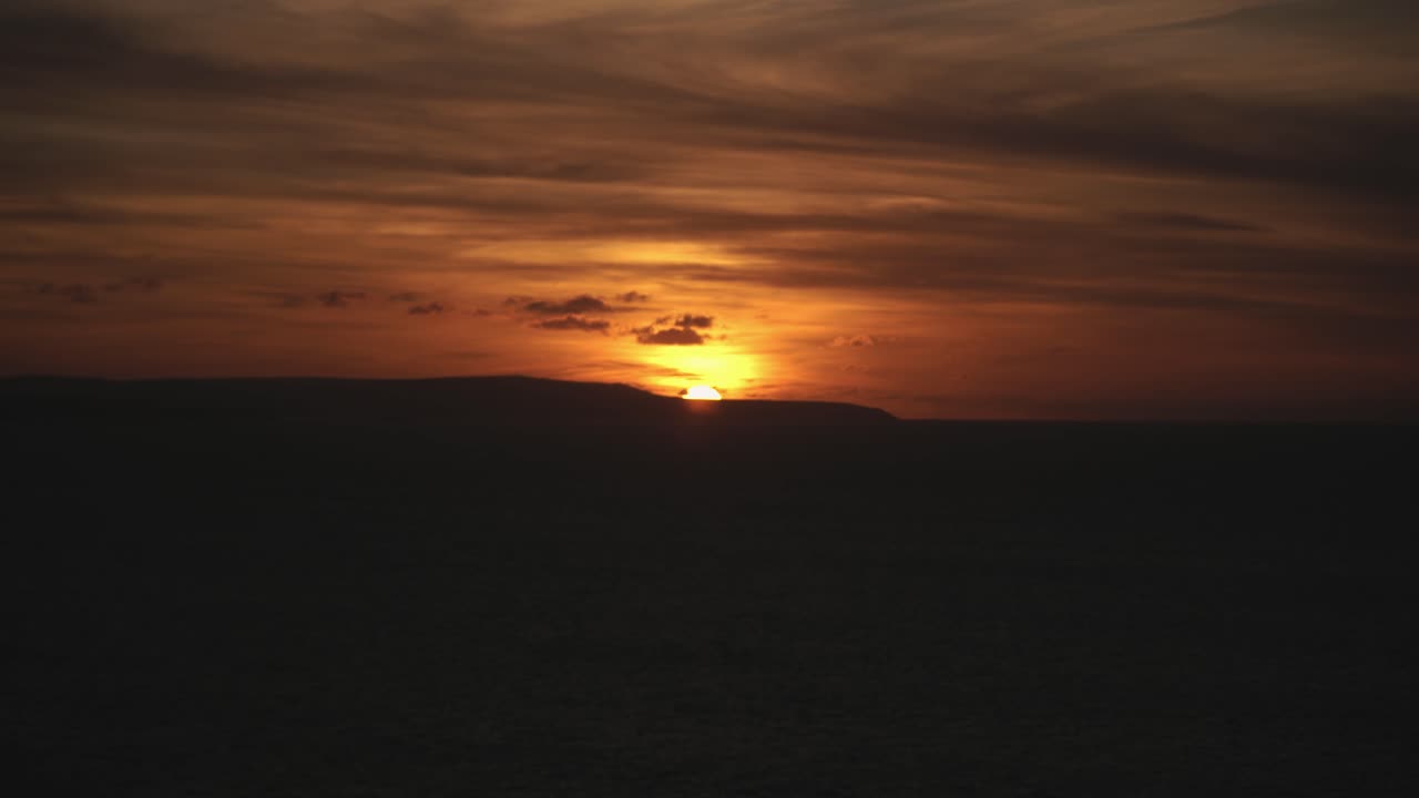 Smuk gylden solnedgang, der lige skjuler sig bag landet i horisonten.