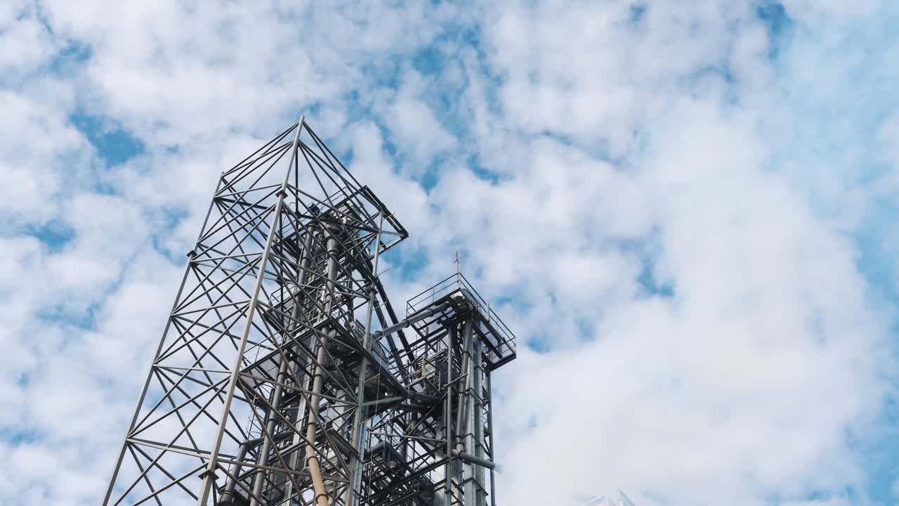 Industrial plant and vapor against the cloudy sky. Thick white steam on metal construction background. Smoke from industry pollutes the air